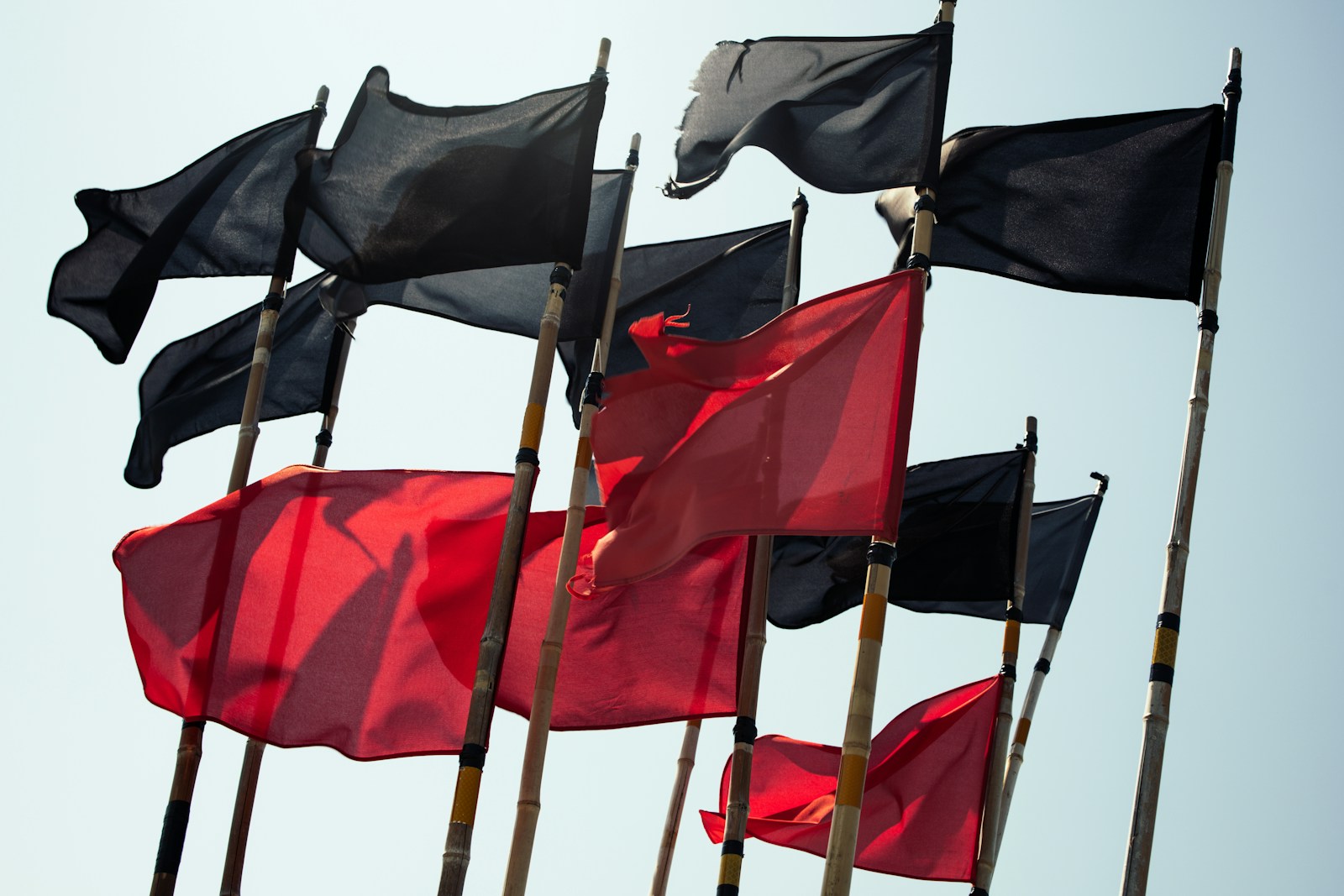 Black and red flags against a blue sky
