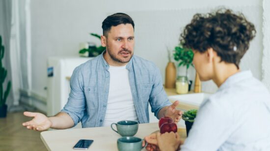 Annoyed man yelling at unhappy wife in kitchen fighting gesturing