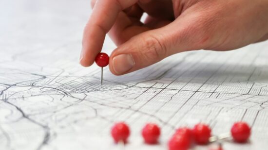Placing red push pins into city street map.